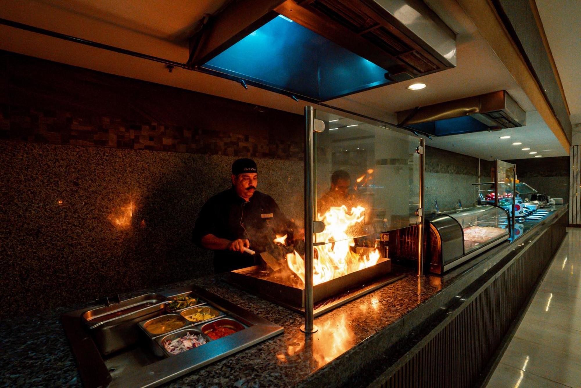 The V Luxury Resort Sahl Hasheesh Hurghada Bagian luar foto A chef cooking with a flaming torch