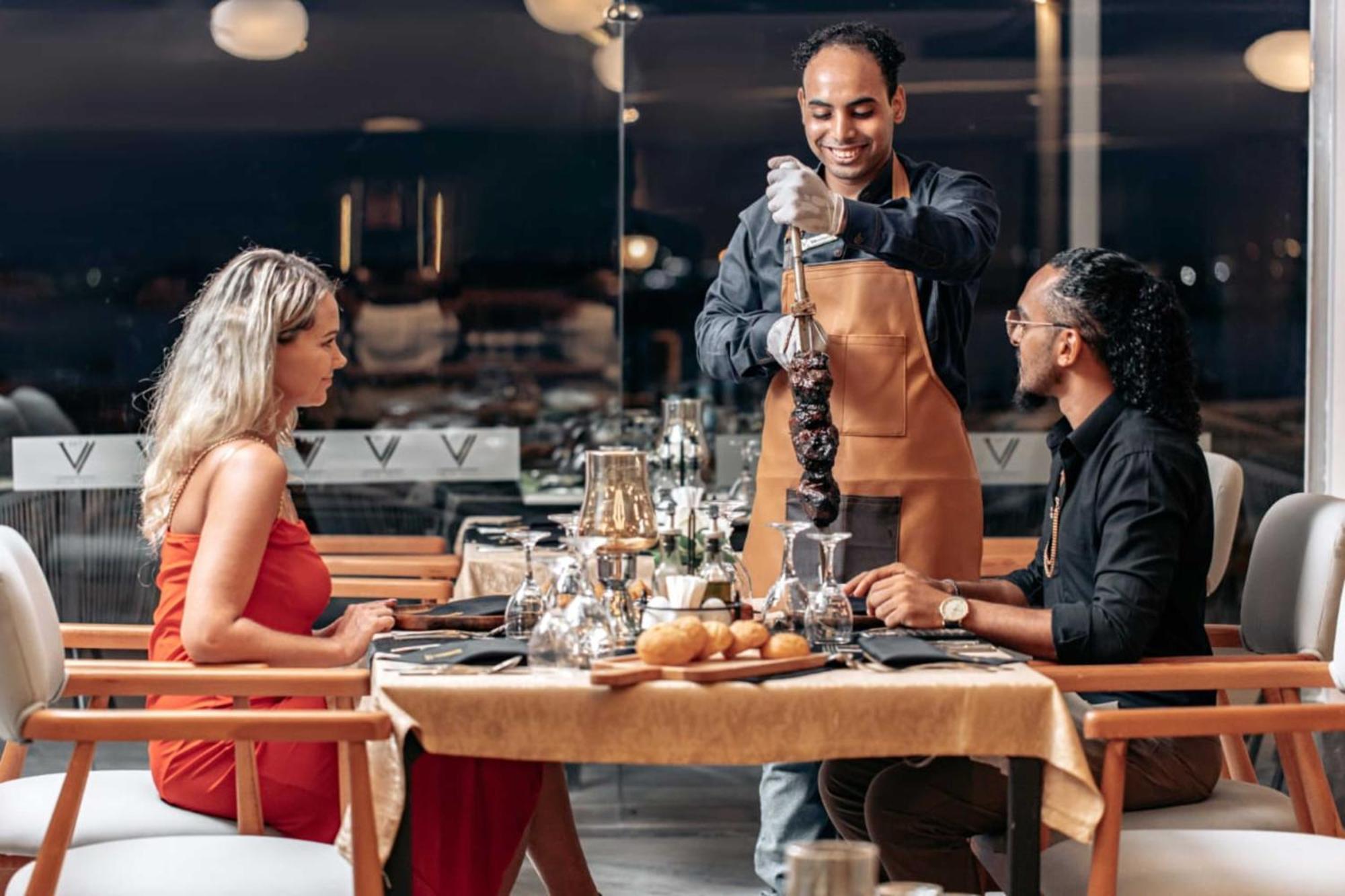The V Luxury Resort Sahl Hasheesh Hurghada Bagian luar foto A waiter serving a couple at a restaurant